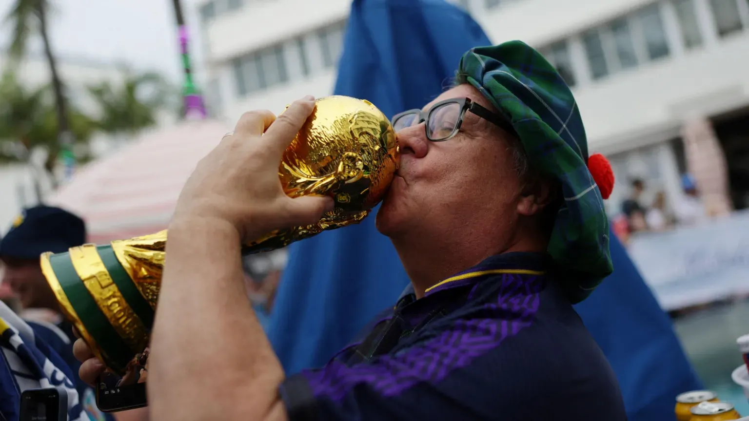 Reuters A man in a Scotland shirt and tartan hat kisses a model of the World Cup trophy