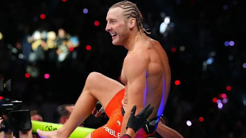 Paddy Pimblett sits on top of the octagon