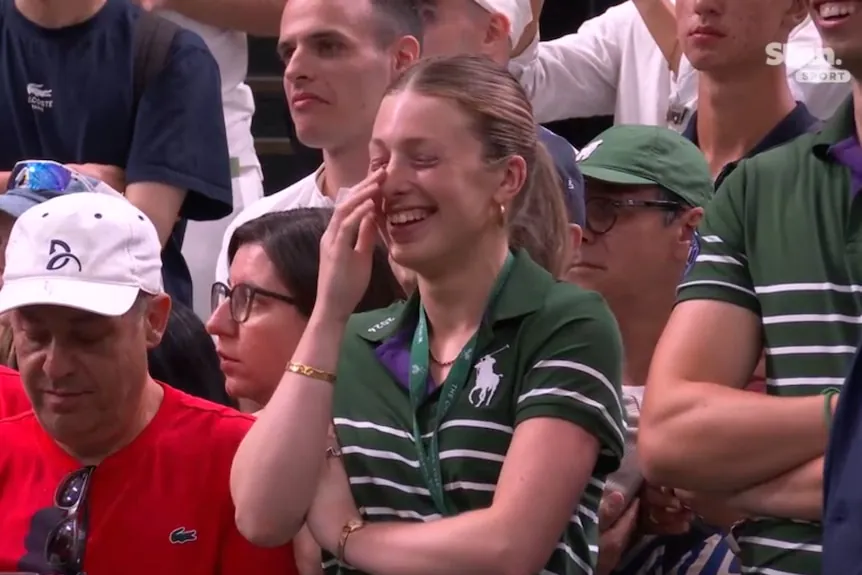A ball kid laughs courtside at Wimbledon after Novak Djokovic's match.